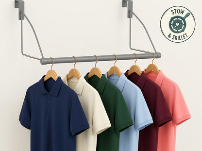 Six short-sleeve polo shirts in navy, cream, green, light blue, burgundy, and coral pink hang on wooden hangers from a gray metal rack mounted on a light beige wall. A circular 'Stow & Skillet' logo appears in the top right corner.
